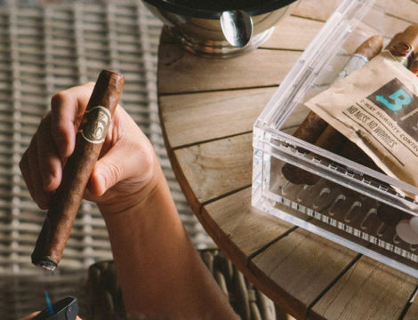 Hand holding lit cigar and humidor with boveda