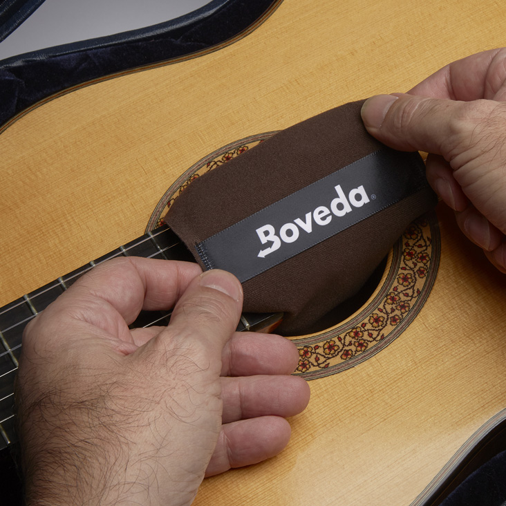 Boveda fabric holder draped over guitar strings and into the sound hole.