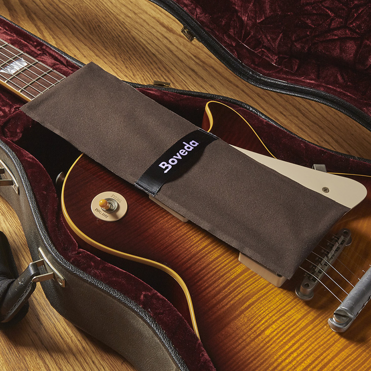 Boveda fabric holder draped over stings on electric guitar.
