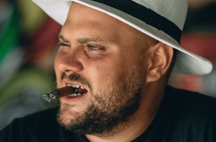 Man in brimmed hat with cigar in mouth held with his teeth