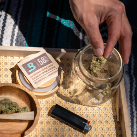 Hand placing cannabis into a jar with Boveda.