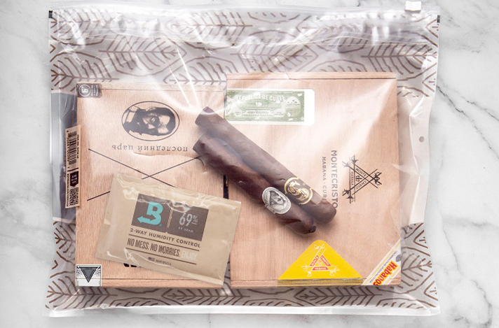 Boveda large humidor bag with two boxes of cigars and two loose cigars inside, along side a Boveda 69% RH size 60.