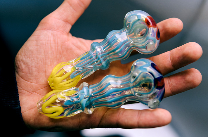 Open hand showing two clean glass marijuana pipes.