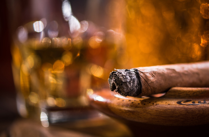 A cigar resting on a wooden ashtray