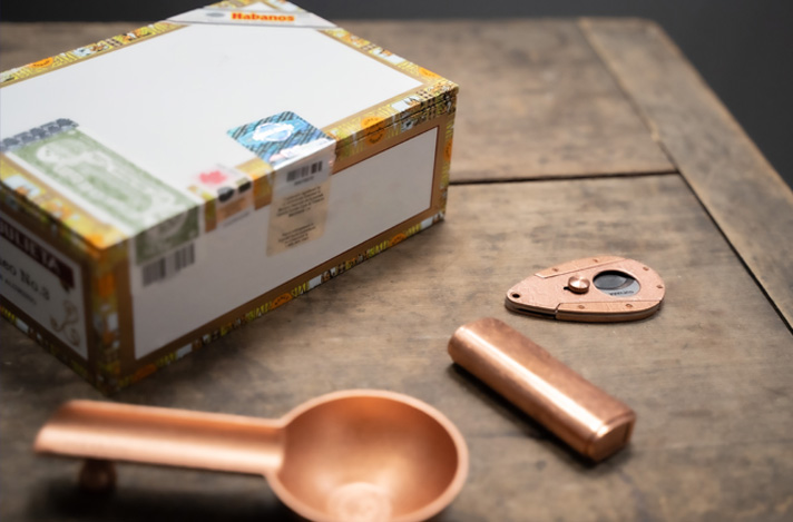 A table with a box of Cuban cigars and a cutter.