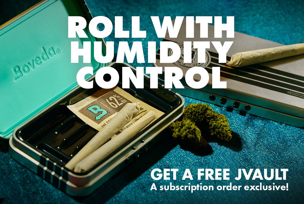 A new open JVault joint holder with Boveda humidity pack and 2 joints inside. Along side is a closed JVault joint holder with 1 joint on top with it and cannabis buds on a blue velour fabric drop cloth.