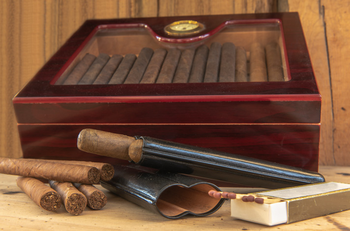 Glass-top humidor with cigars and some matches.