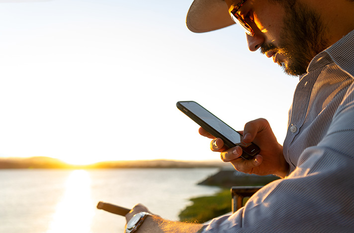 A man looking at his phone while smoking a cigar