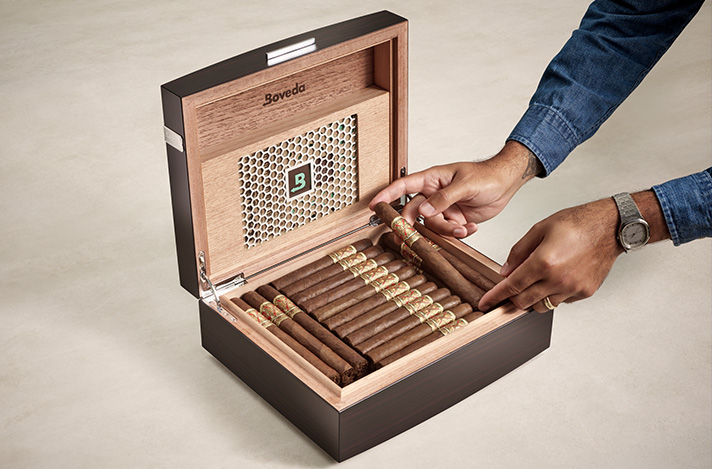 Boveda Humidor with hands placing cigars in it