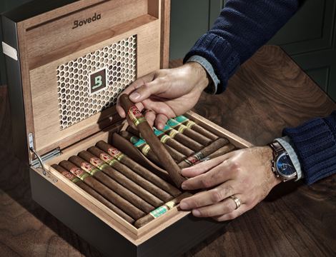 Hands removing a cigar from a Boveda humidor.